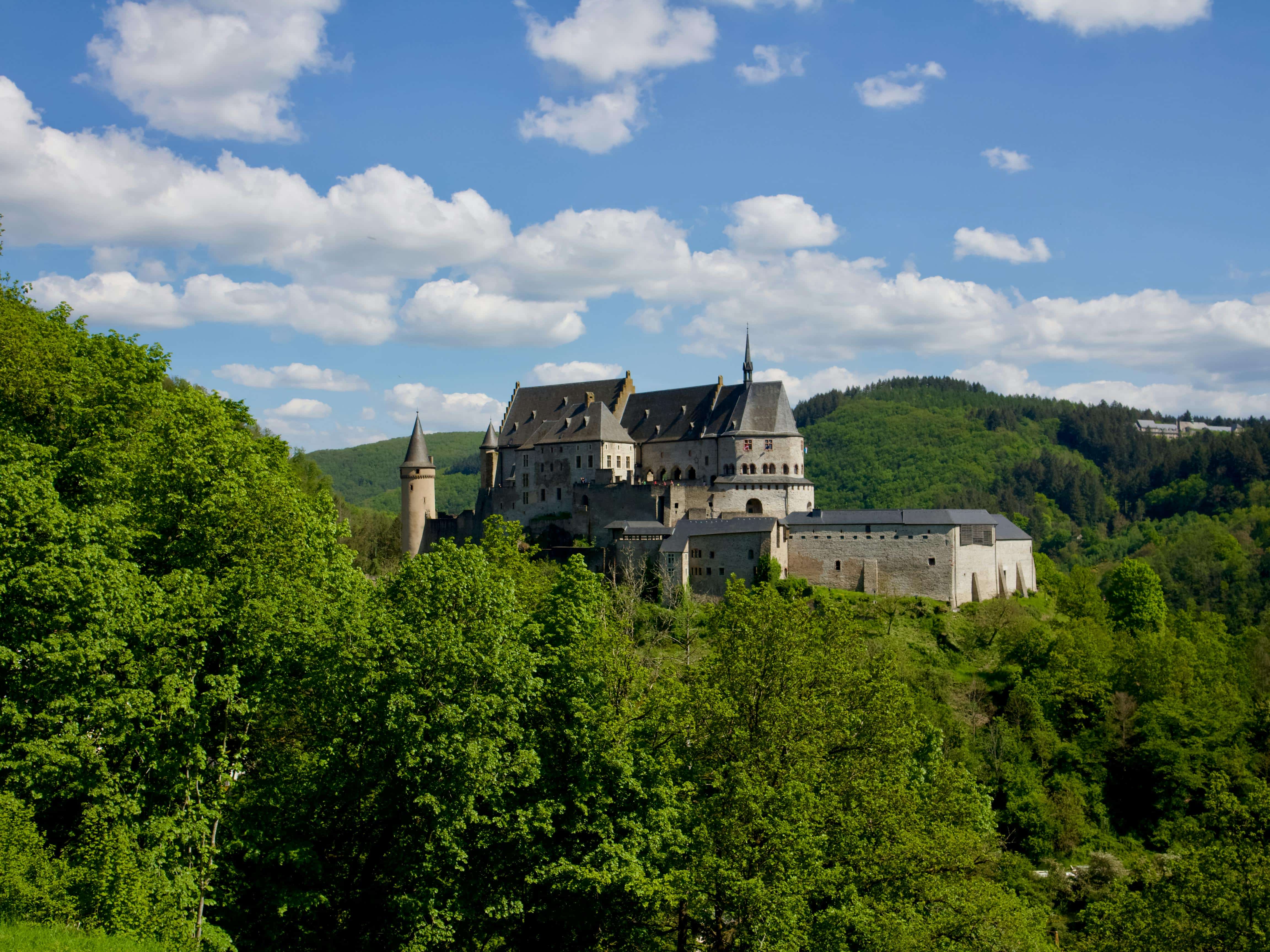 A stunning aerial view of Vianden Castle surrounded by lush forests in Luxembourg.
